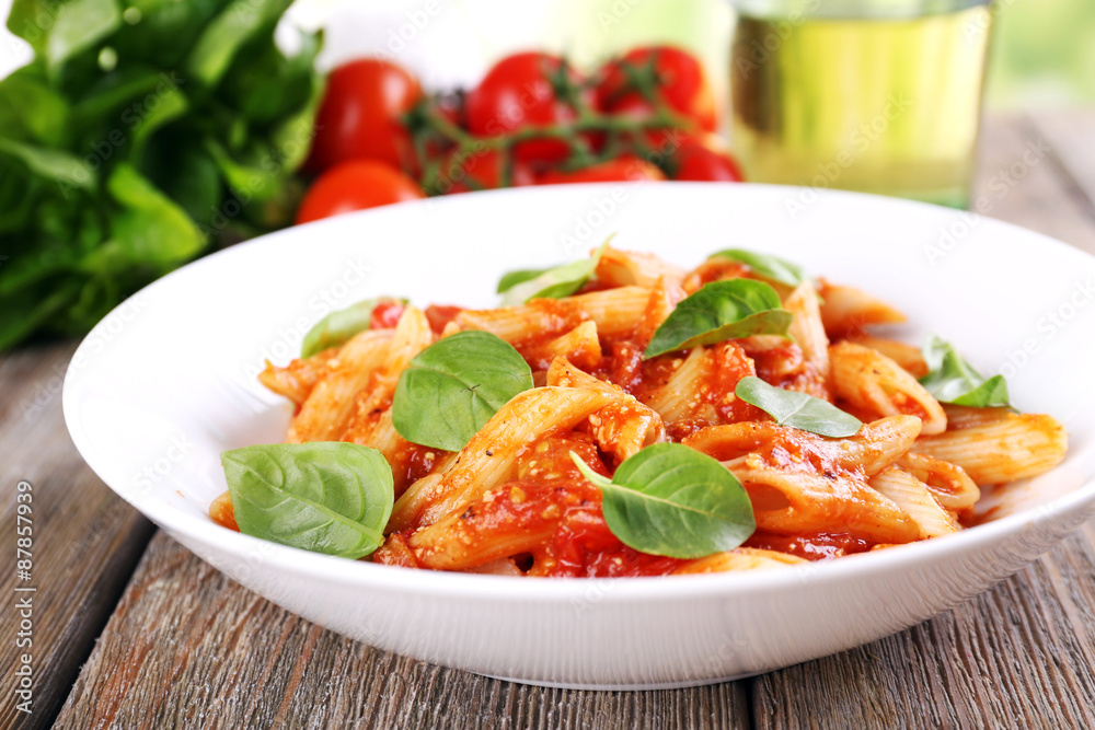 Pasta with tomato sauce and basil on table close up Pasta with tomato sauce and basil on table close up