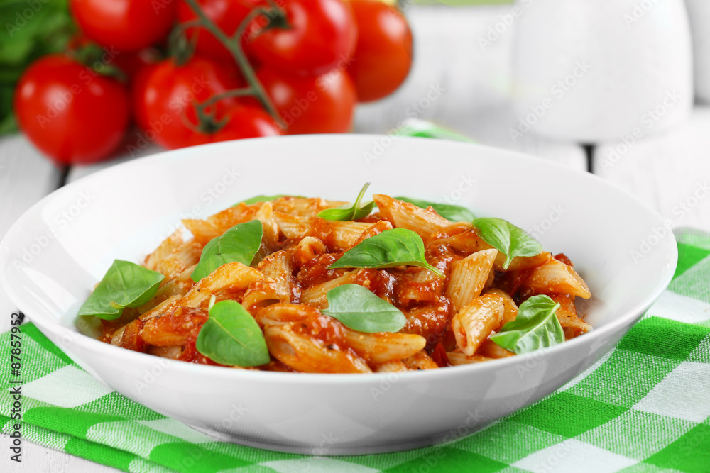 Pasta with tomato sauce and basil on table close up Pasta with tomato sauce and basil on table close up