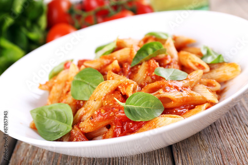 Pasta with tomato sauce and basil on table close up