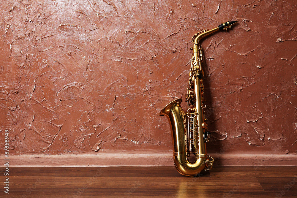 Naklejka premium Golden saxophone on brown wall background