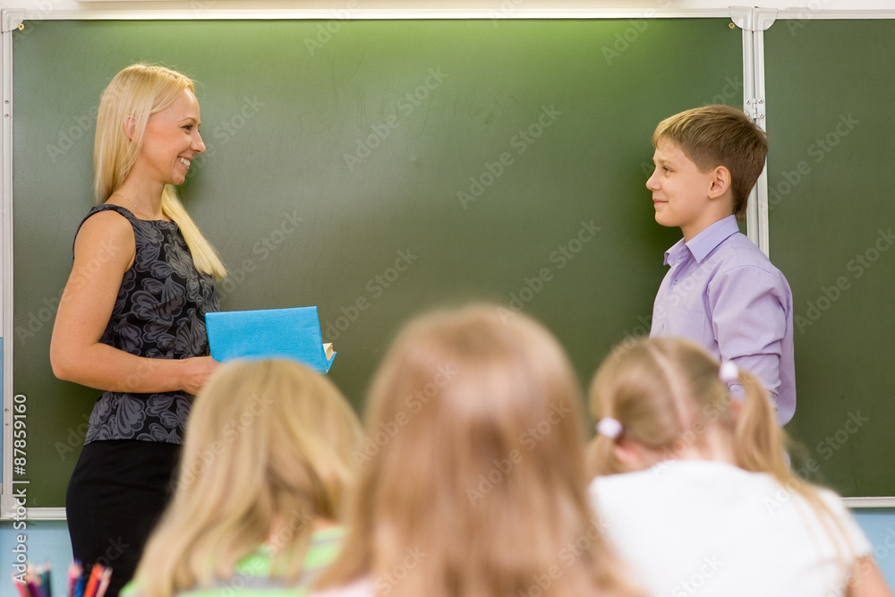 Boy answers questions of teachers near a school board Boy answers questions of teachers near a school board