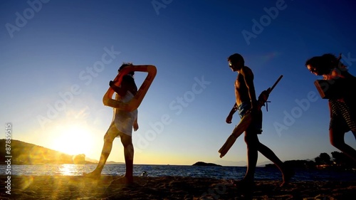 SUMMER VACATION CONCEPT. Silhouette tourists walking with beach accessories at sunset  tropical resort photo