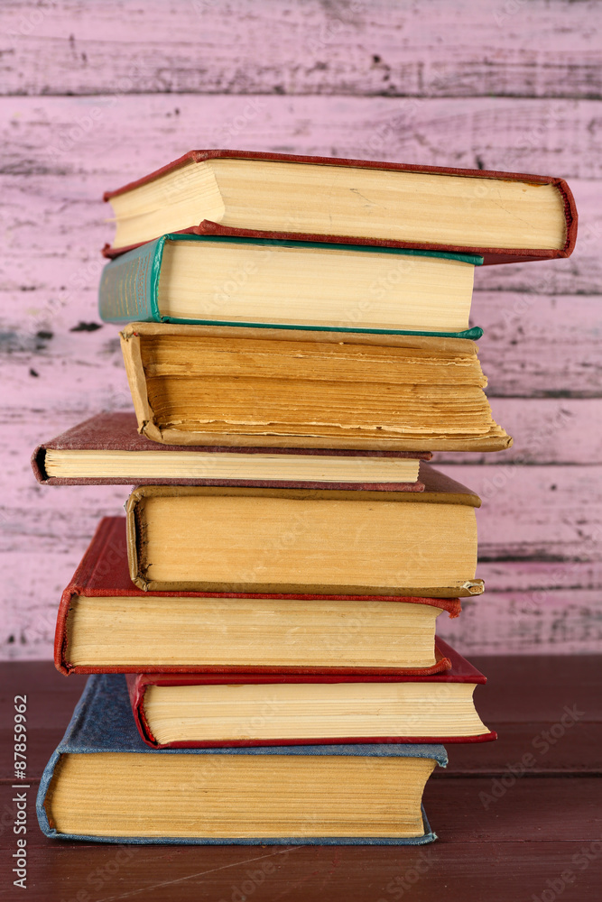 Stack of books on wooden table on pink wooden wall background Stack of books on wooden table on pink wooden wall background