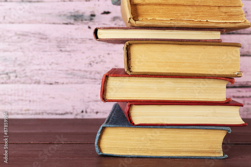 Stack of books on wooden table on pink wooden wall background