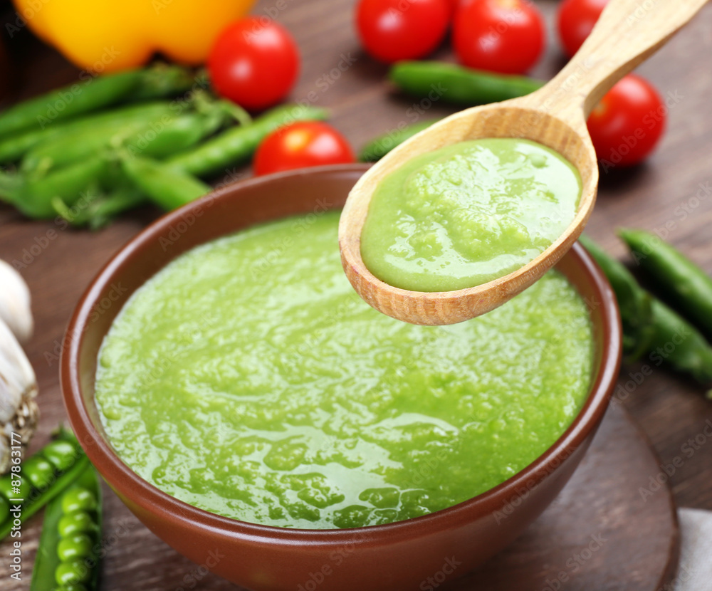 Tasty peas soup and vegetables on table close up Tasty peas soup and vegetables on table close up