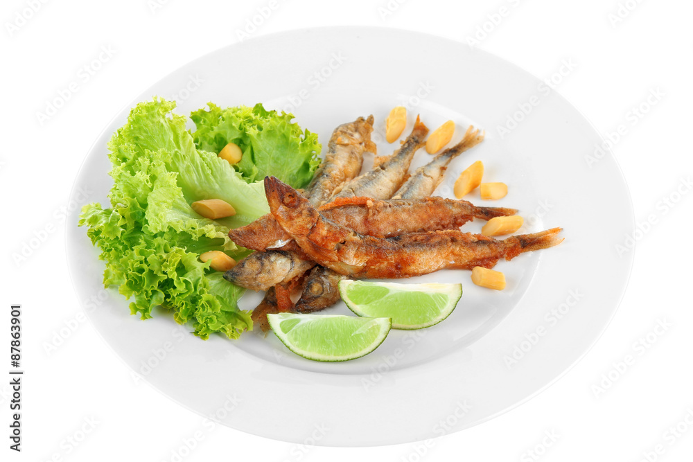 Fried small fish on plate with lettuce and lime isolated on white Fried small fish on plate with lettuce and lime isolated on white