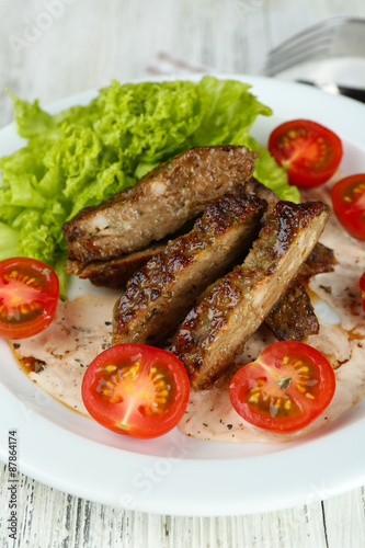 Tasty slices of meat with sauce and cherry tomato on table close up