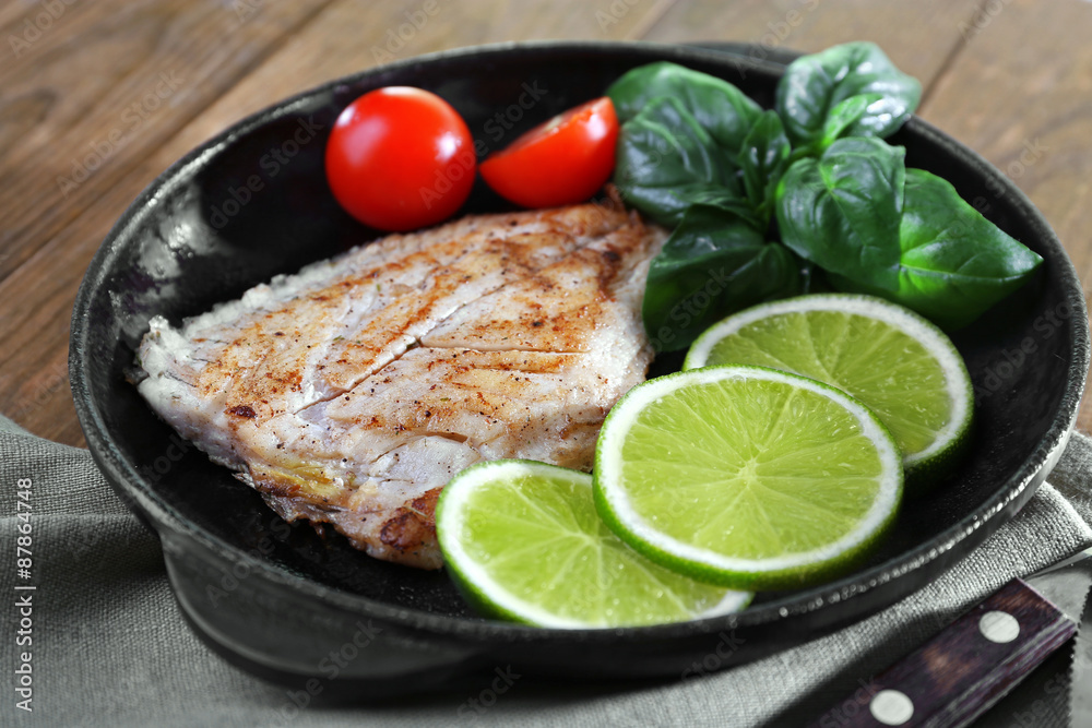 Dish of fish fillet with salad and lime on table close up