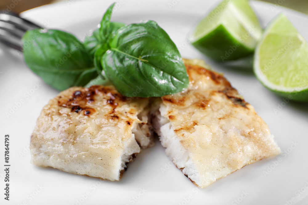 Dish of fish fillet with basil and lime on plate close up Dish of fish fillet with basil and lime on plate close up