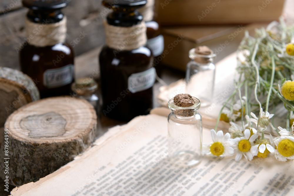Old book with dry flowers and bottles on table close up Old book with dry flowers and bottles on table close up