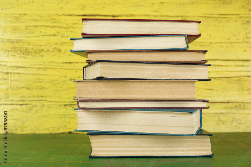 Stack of books on yellow wooden background Stack of books on yellow wooden background