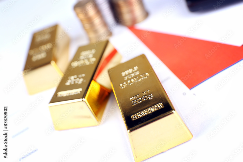 Gold bullion with coins on documents background Gold bullion with coins on documents background