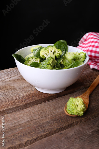Fresh broccoli with spinach in bowl on dark background