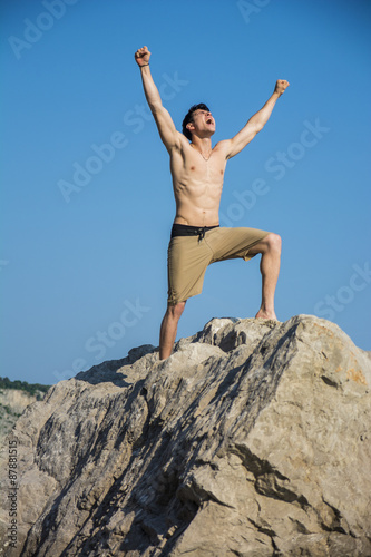 Successful sexy muscular shirtless man with fists raised