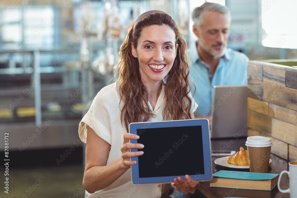 Pretty brunette looking at camera and showing tablet Pretty brunette looking at camera and showing tablet