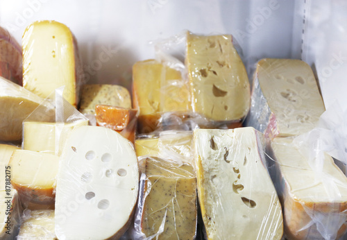 Set of cheese in plastic bags on shelf of fridge