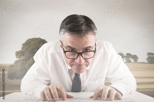 Composite image of mature businessman typing on keyboard