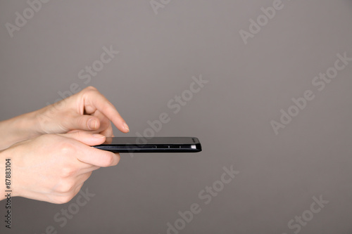 Female hands using mobile phone on gray background