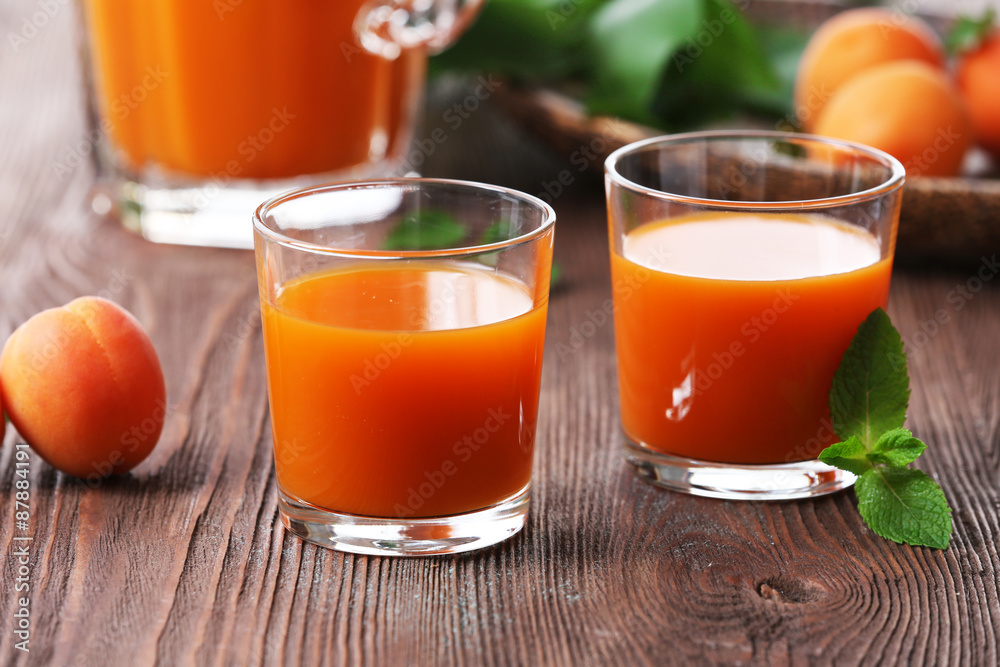 Glasses of apricots juice on wooden table, closeup