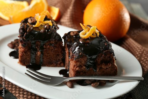 Portion of Cake with Chocolate Glaze and orange on plate, on wooden background