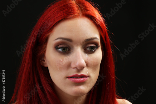 Fototapeta Naklejka Na Ścianę i Meble -  Face of young woman with tear drop on dark background