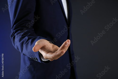 Businessman in suit introduce something on dark background © Africa Studio