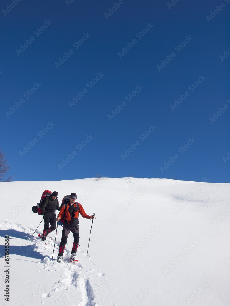 Men go snowshoeing in the mountains in the snow.