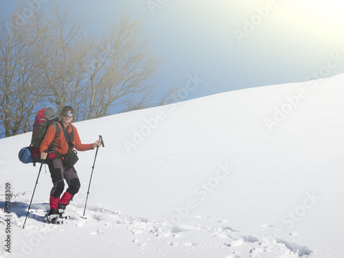 A man in snowshoes is in the mountains in the snow.