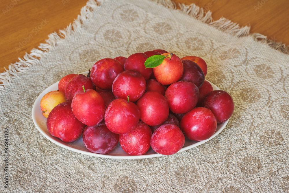 Plums in the white plate on wooden table Plums in the white plate on wooden table