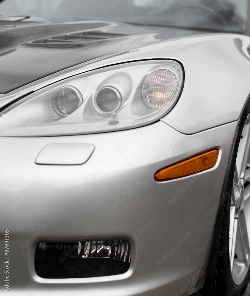 Close-up view of silver sports car headlight.