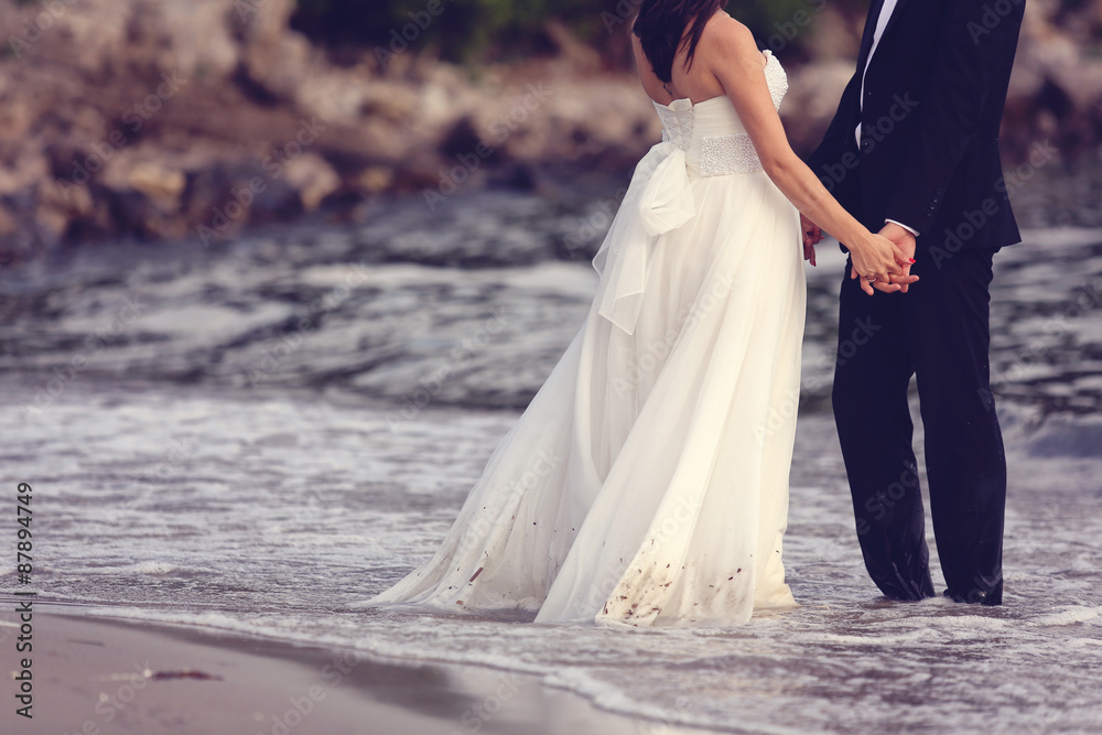Bride and groom holding hands at the beach