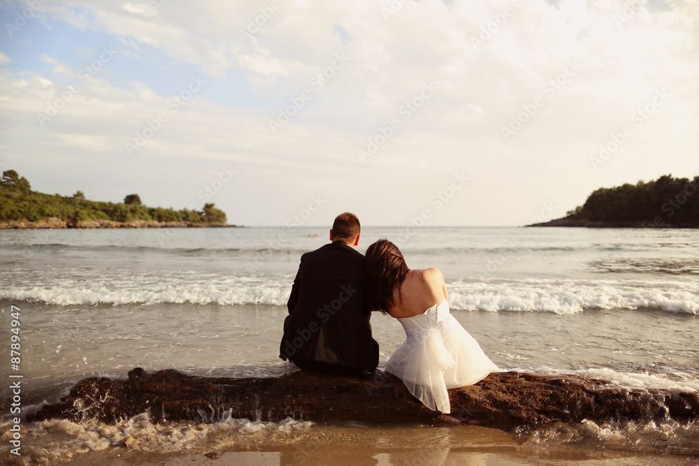 Bride and groom sitting by the beach