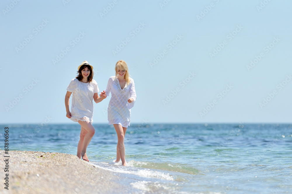 Two womans in white dress running on the beach