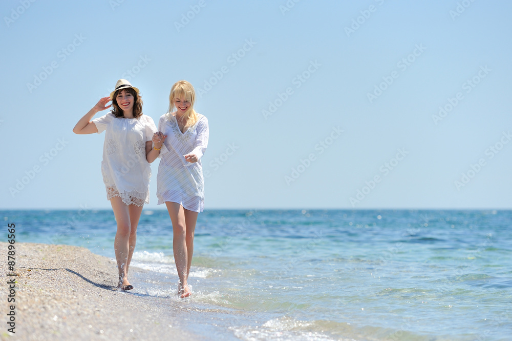 Two womans in white dress running on the beach