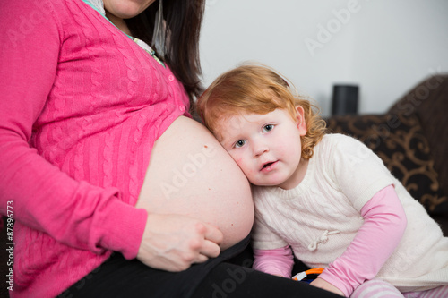 Mutter und ihre Tochter spielen mit dem Babybauch