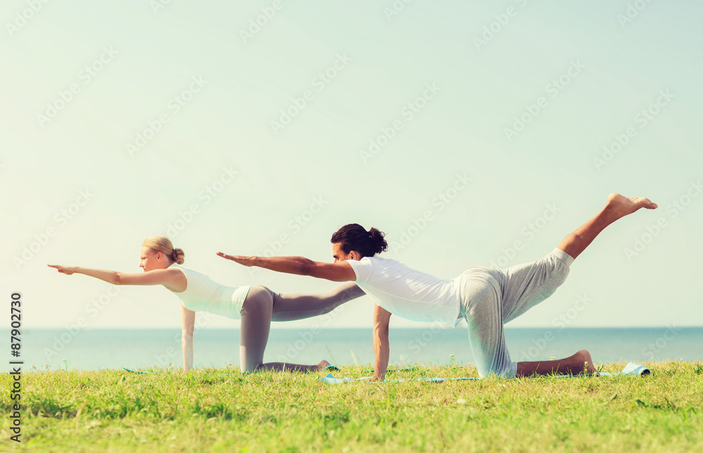 smiling couple making yoga exercises outdoors smiling couple making yoga exercises outdoors