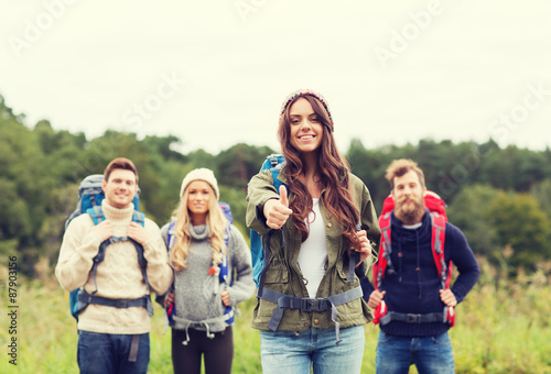 group of smiling friends with backpacks hiking