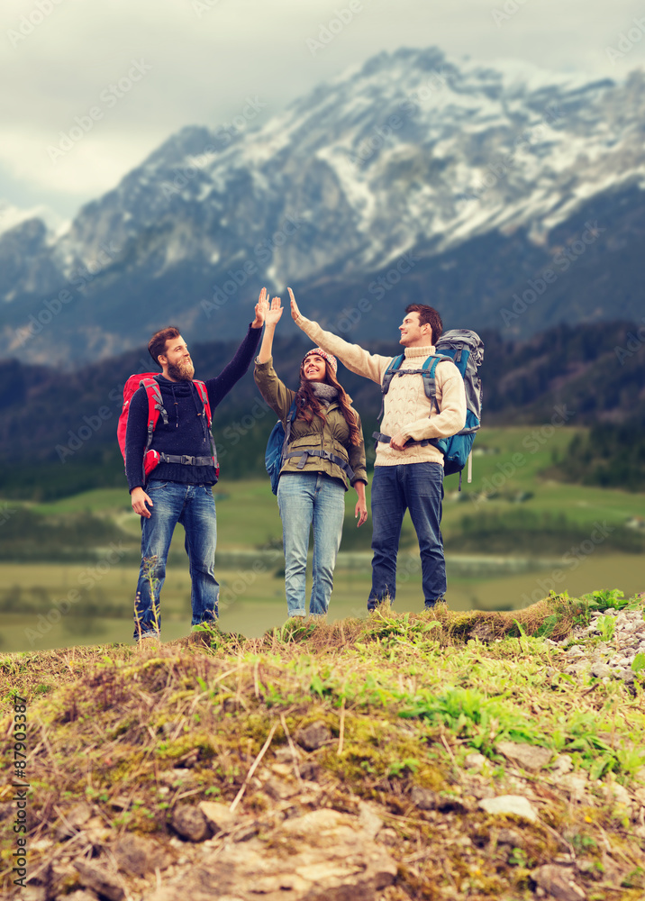 group of smiling friends with backpacks hiking