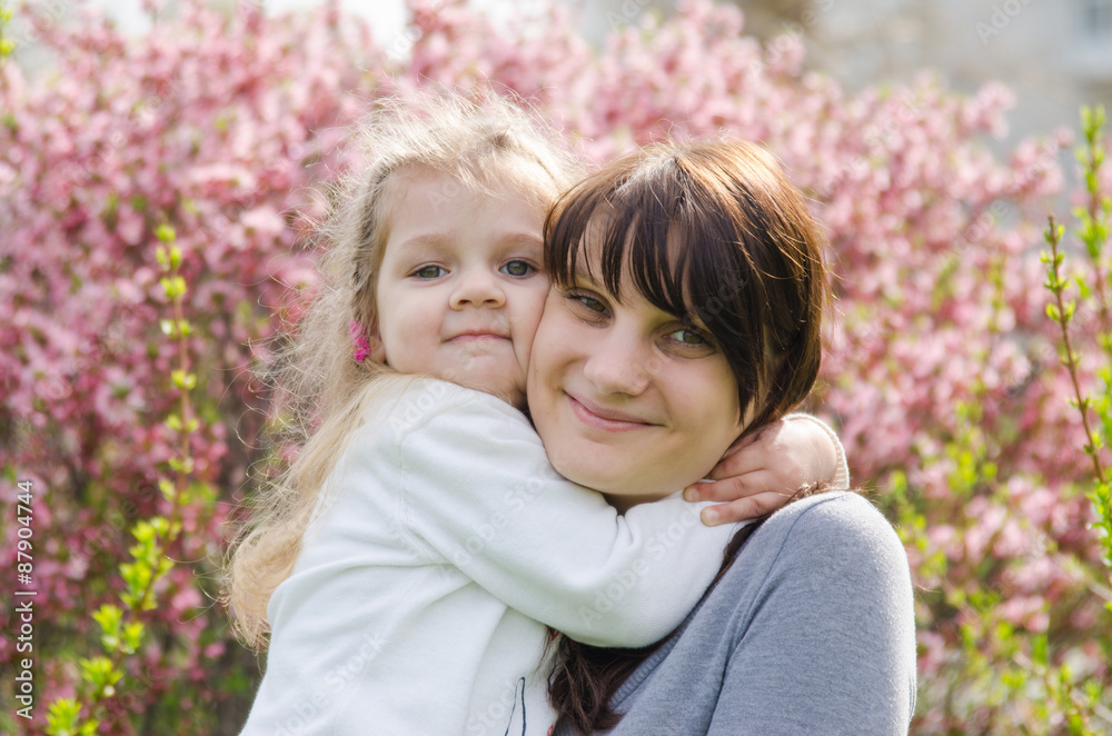 Embraces of mother and daughter on spring background