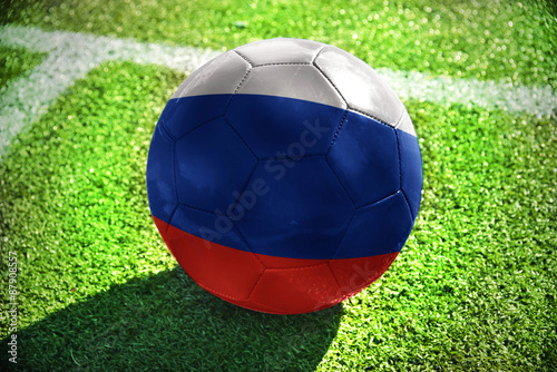 football ball with the national flag of russia lies on the green field near the white line