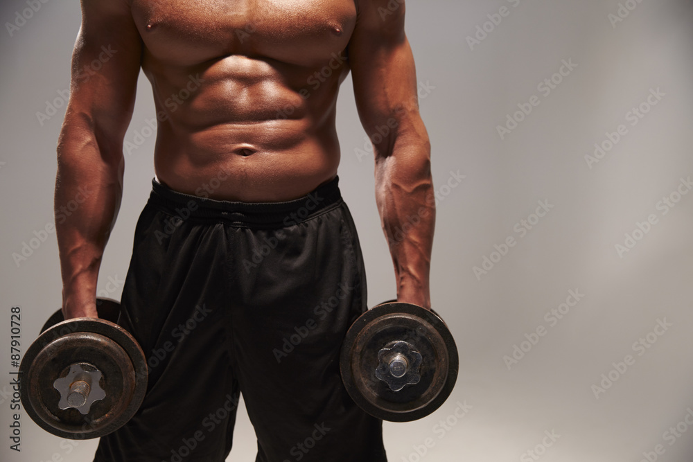 Male bodybuilder working out with heavy dumbbells, with copy spa Male bodybuilder working out with heavy dumbbells, with copy spa