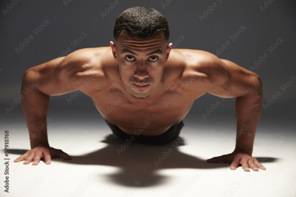 Muscular, shirtless young man doing press-ups