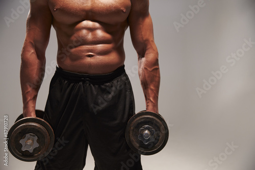 Male bodybuilder working out with heavy dumbbells, with copy spa