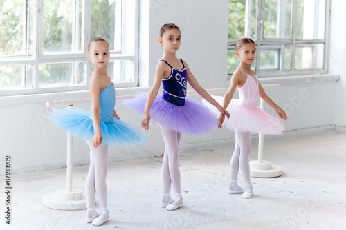 Three little ballet girls sitting in tutu and posing together