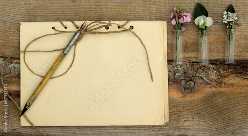 handmade notebook with old pen and small bouquet of wildflowers on a wooden background