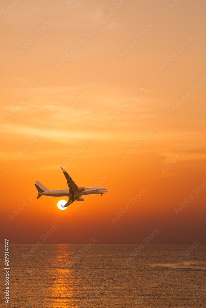Commercial airplane flying above the sea at sunset