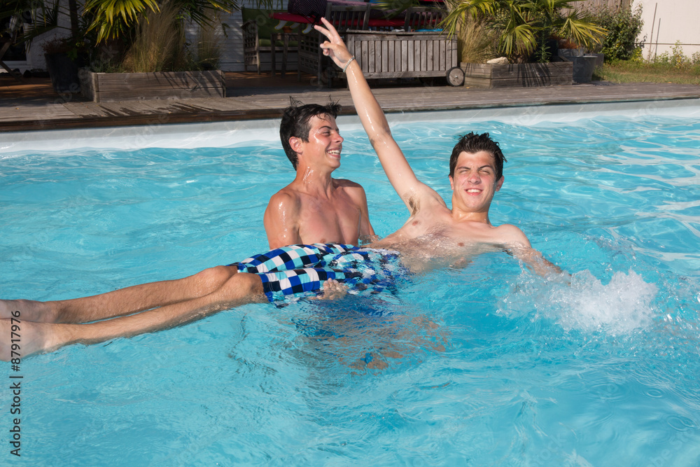 Portrait of two teenager splashing water together in pool