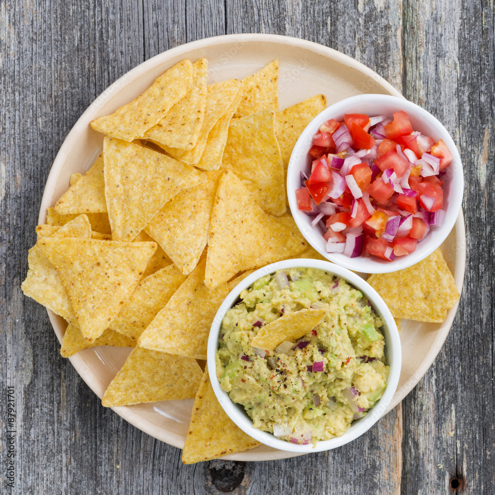 guacamole, tomato salsa and corn chips on a plate, top view guacamole, tomato salsa and corn chips on a plate, top view