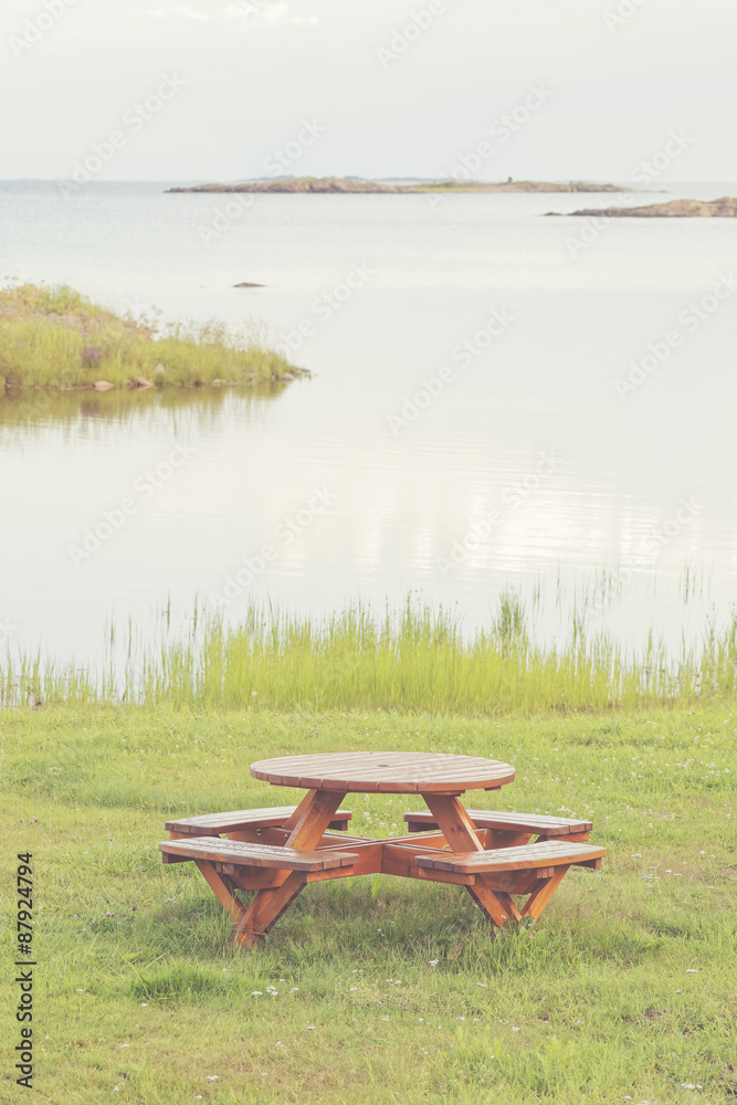 Fototapeta premium Bench at seashore with lush grass and view over the seascape