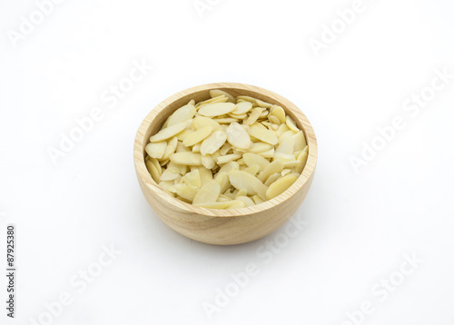 Almond slices in wooden bowl on white background